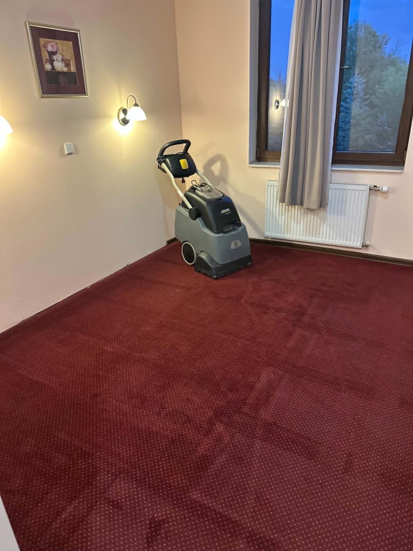 Maszyna ekstrakcyjna w pokoju hotelowym z bordową wykładziną